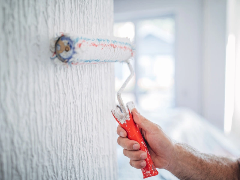 man-using-roller-paint-brush-to-put-primer-on-over-textured-wall