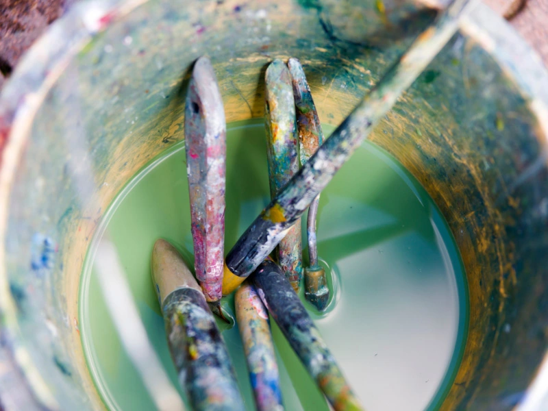 bucket-with-paint-tools-sitting-in-green-colored-water