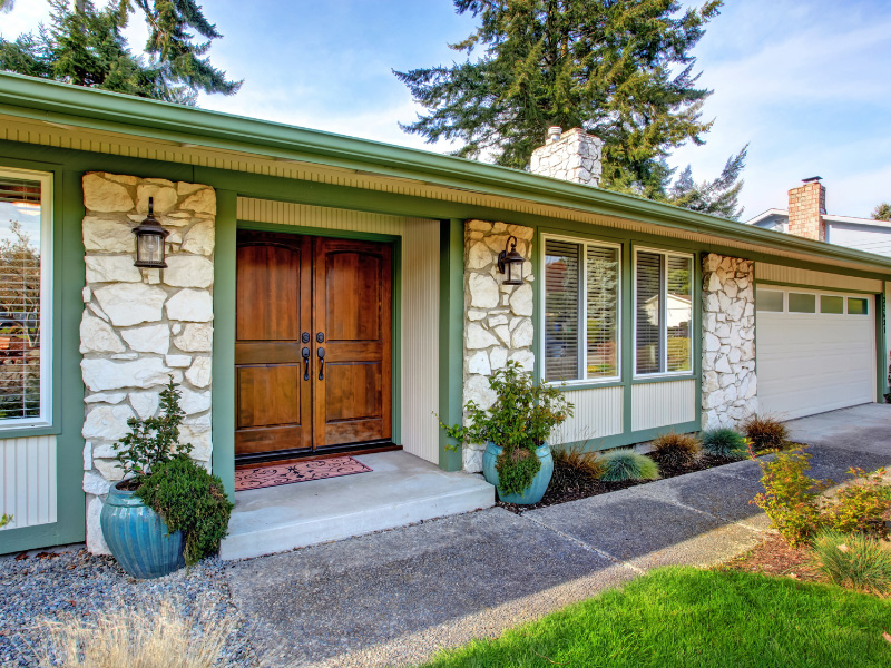 cream-colored-house-with-stone-veneer-siding-and-dark-green-house-trim-and-stained-wooden-front-door-close-up