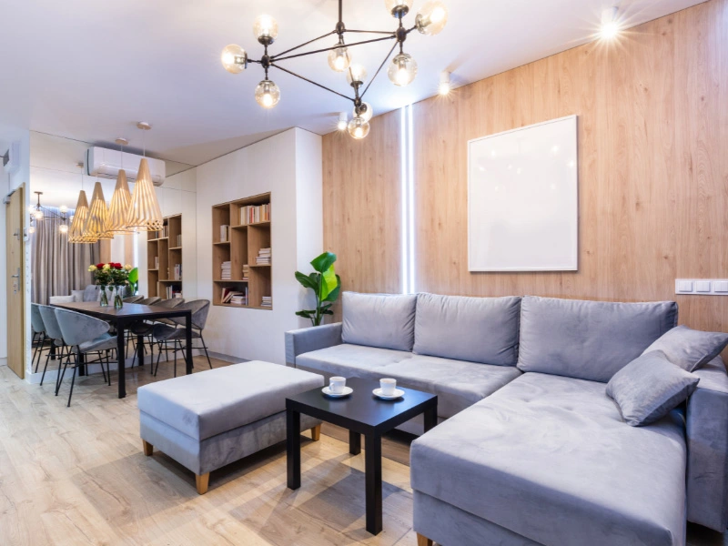 living-and-didng-room-space-with-natural-wood-accent-wall-in-living-area-gray-furnishings-and-circle-light-fixtures