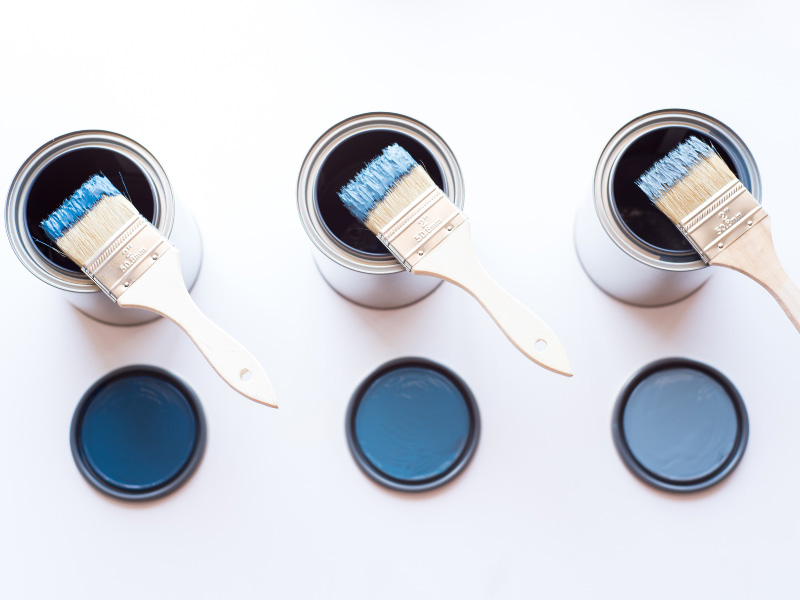 three-shades-of-blue-paint-cans-open-with-a-paint-brush-dipped-in-the-color-set-atop-each-can