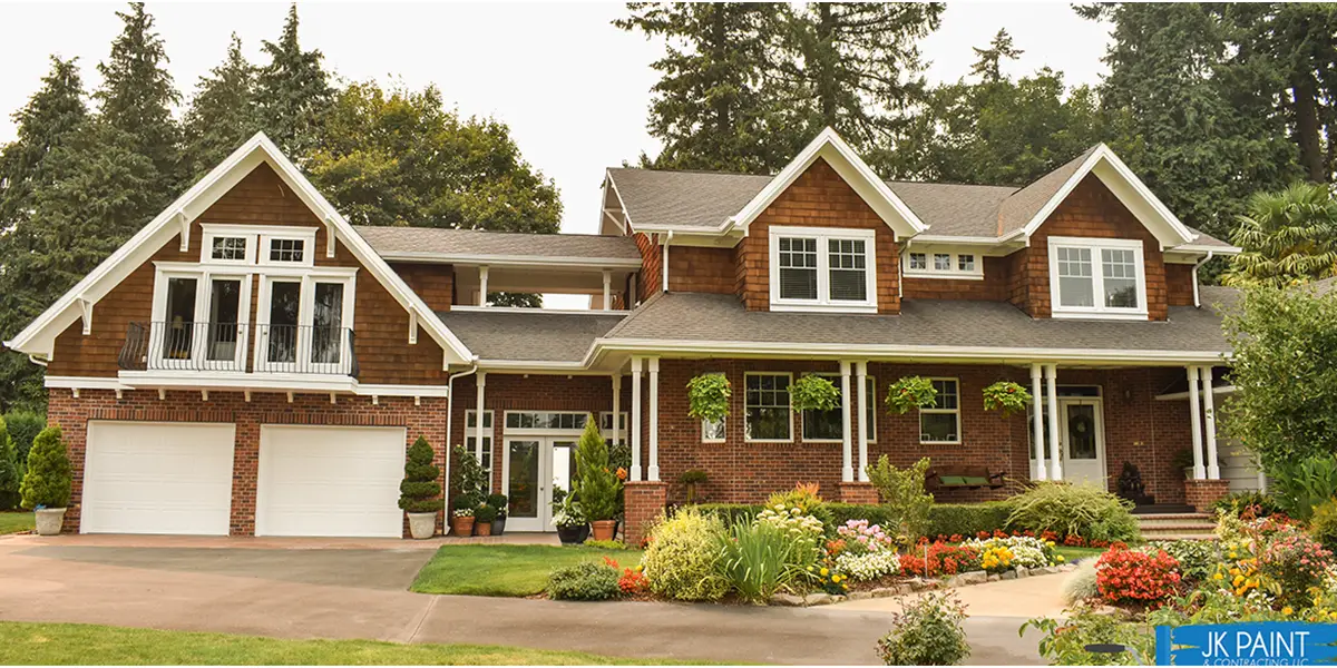 large-brown-house-with-brick-foundation-and-white-trim-beautiful-garden-and-plants