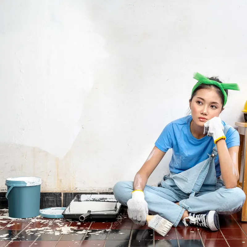 Photo asian young woman in a glove holding a paintbrush with an unhappy expression