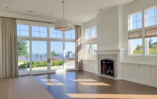 Bright empty living room with white walls, fireplace, and tall windows