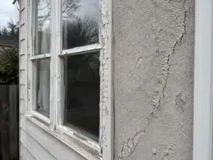 damaged-paint-stucco-and-wood-exterior-home an exterior painting contractor caulking a house
